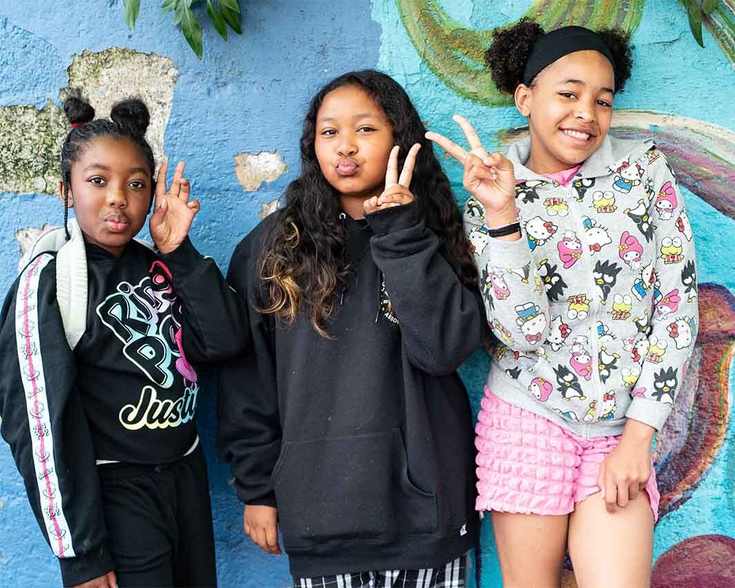 Three 4/5th grade students smile and pose with peace signs.