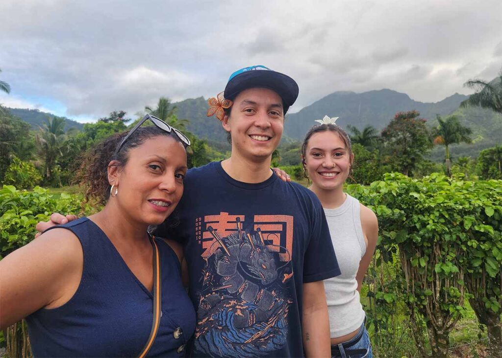 Vashti and her grown son and daughter stand in a lush landscape in Kauai, Hawaii.