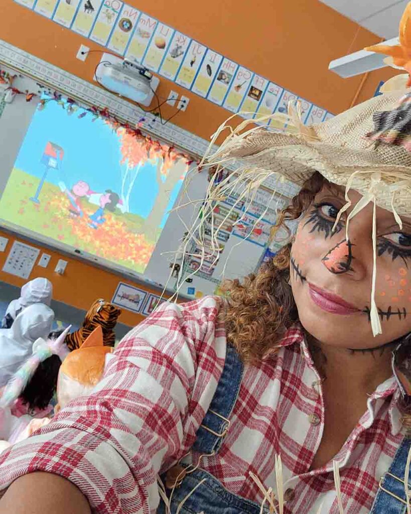 Ms. Vashti in her classroom and dressed up as a scarecrow for Halloween.