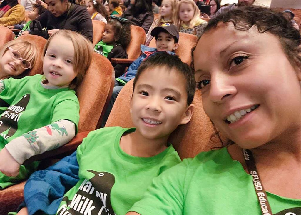Ms. Vashti and some students in green Harvey Milk shirts, sitting in seats at the SF Symphony.