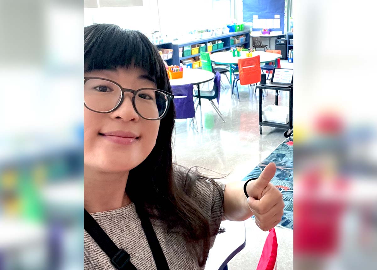 Ms. Vee gives a thumbs up in her classroom.