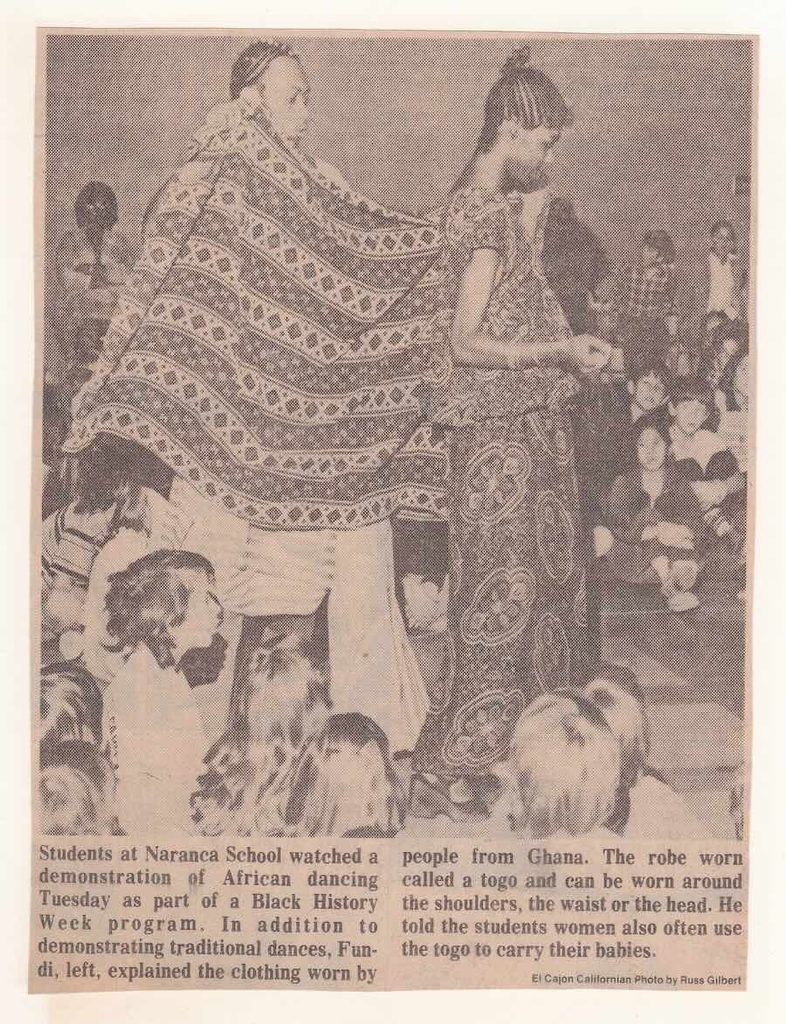 Newspaper article with students and performers in African clothes performing a dance.